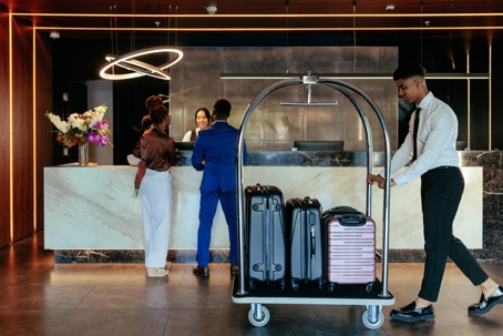 Hotel attendant with luggage in lobby. stock photo
